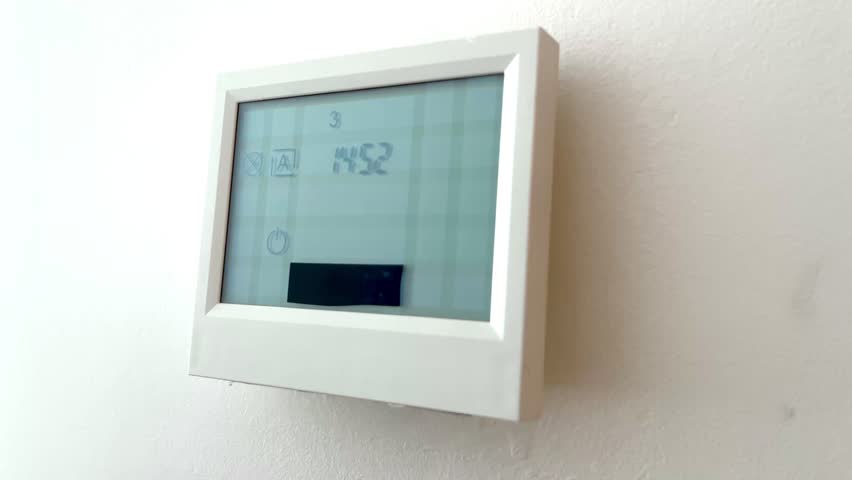 close-up of a finger switching a heating thermostat from manual to automatic mode on a touchscreen, reducing energy consumption in winter