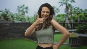 Young hispanic woman wearing green crop top giving double thumbs up in open forest setting; approval. - Powered by Shutterstock - Get 15% off with code: PIKWIZARD15
