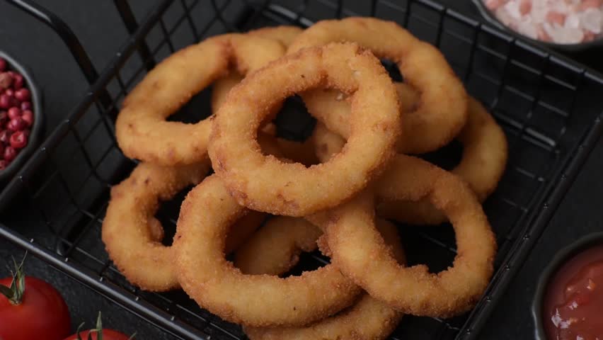 Onion rings or fried squid in breadcrumbs with sauce, takeaway food. Onion rings fried, fast food as a background for your design
