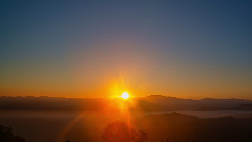 Time lapse beautiful sun shine above the mist in the valley
slow floating fog blowing cover on the top of mountain look like as a sea of mist. 
white cloud in blue sky over the perfect forest.