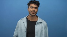 Man with earring in black shirt and light denim overshirt holds neck with hand in a blue studio set; serenity ease comfort. - Powered by Shutterstock - Get 15% off with code: PIKWIZARD15