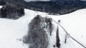 Peaceful winter drone footage showing a small countryside chapel surrounded by snowy fields, forest and mountain landscape near Ruzomberok. Scenic calm atmosphere and clean 4K aerial view. - Powered by Shutterstock - Get 15% off with code: PIKWIZARD15