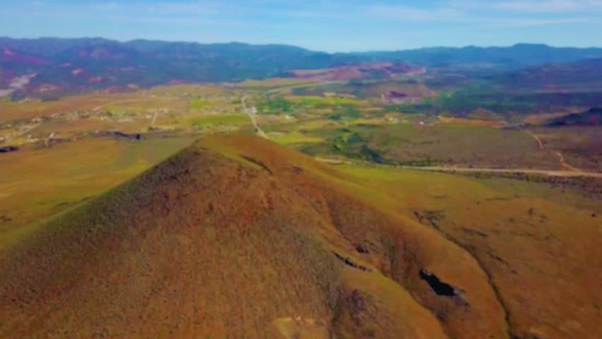 Experience the dramatic landscapes of a dormant volcano with this cinematic aerial pan. The footage captures the volcano’s rugged slopes, volcanic cone, and surrounding terrain, while a highway winds 