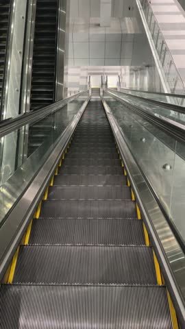 Empty escalator moving downward in a clean, futuristic interior space.
