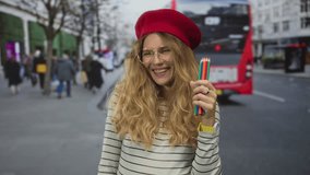 Woman holding pencils blowing a kiss in the middle of a street features a blonde young muse inspired by kiss graffiti across a city mural beside a colorful beret. - Powered by Shutterstock - Get 15% off with code: PIKWIZARD15