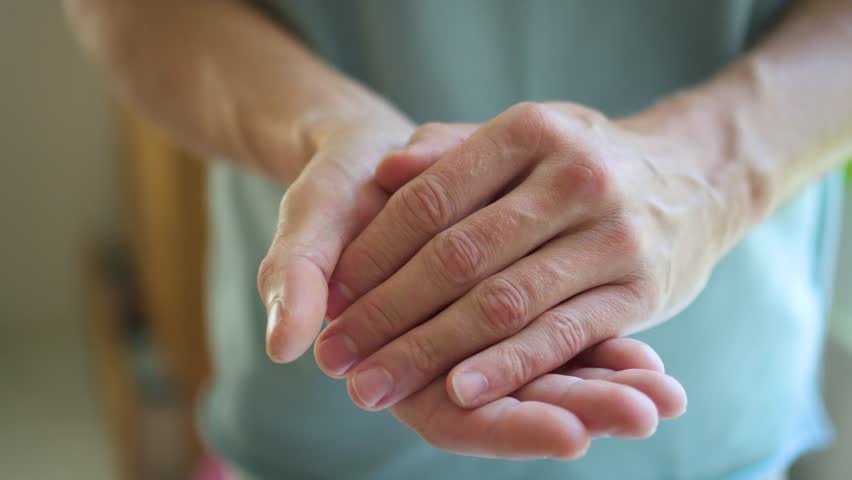 Close-up of male hands opening to reveal red satin ribbon on palm, symbolizing HIV AIDS support, remembrance, and hope for future cure.