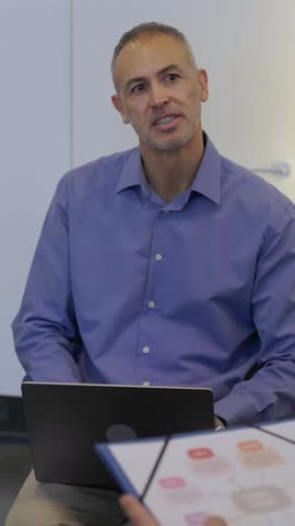Vertical HD video of mature businessman leading group conversation with his team. Business and teamwork concept.