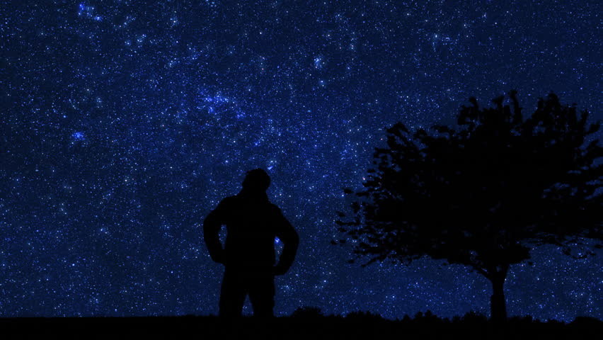 Silhouette of a man and countryside under the Milky Way stars.
