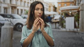 Hispanic brunette young woman blowing a kiss with both hands near mouth on a cobbled street in town; playful flirtation. - Powered by Shutterstock - Get 15% off with code: PIKWIZARD15