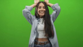 Young woman raising hands above head showing midriff and smiling wearing casual shirt and jeans in studio; joyful play. - Powered by Shutterstock - Get 15% off with code: PIKWIZARD15