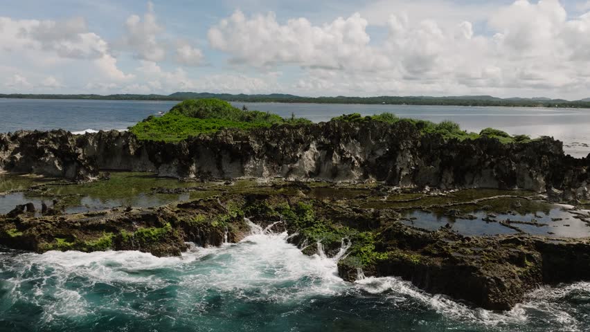 Aerial drone of coastline with tidal pools and waves washing over the shore. Siargao, Philippines.