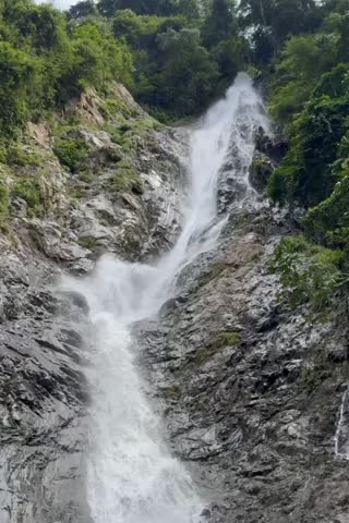 Powerful waterfall crashes rapidly down rugged cliff.