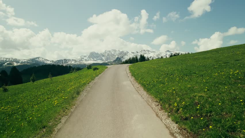 A bright blue lake lies between rocky mountains with snow-capped peaks and sparse vegetation, capturing a serene alpine landscape with clear water and dramatic scenery.