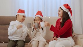 Happy christmas family at home celebrating holiday parent and two children enjoy warm drinks wearing festive santa hats, presents visible, lights glow on cozy sofa for kids and adults. - Powered by Shutterstock - Get 15% off with code: PIKWIZARD15