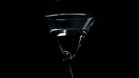 Slow-motion of an olive dropping into a martini glass on a black background, capturing elegant cocktail preparation and mixology moments. - Powered by Shutterstock - Get 15% off with code: PIKWIZARD15