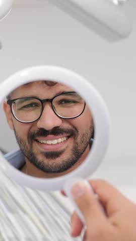Beautiful video of an attractive young man with a beautiful smile in a round dental mirror. 