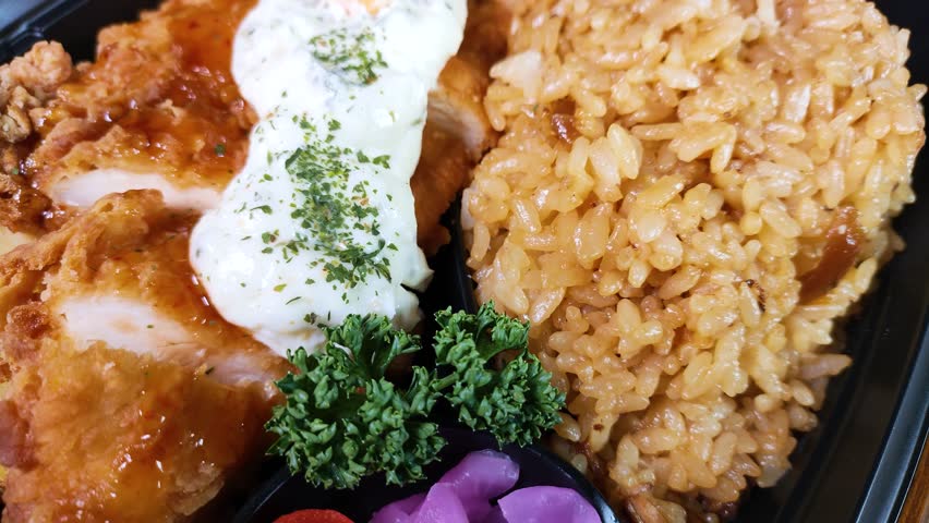 Japanese chicken nanban bento close up, rotating.  Chicken Nanban is fried chicken marinated in sweet and sour sauce and topped with tartar sauce, it is a local gourmet dish from Miyazaki Prefecture.