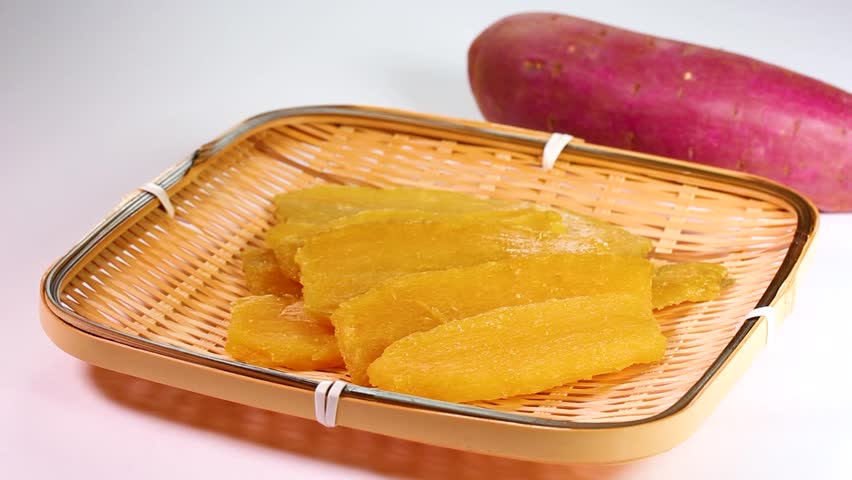 Dried sweet potato on a bamboo colander and a Sweet potato, rotating