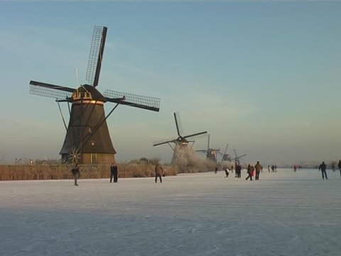 Ice skating along the windmills at the Kinderdijk in wintertime in the Netherlands