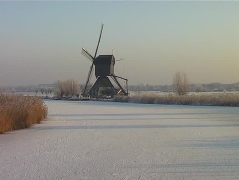 Ice skating along the windmills at the Kinderdijk in wintertime in the Netherlands