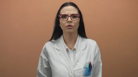Scientist wearing glasses in white uniform gestures against brown wall, conveying engagement with audience, highlighting professional environment and communication. - Powered by Shutterstock - Get 15% off with code: PIKWIZARD15