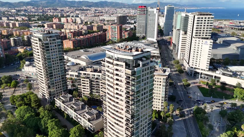 Dynamic drone shot approaches a modern high-rise in Barcelona