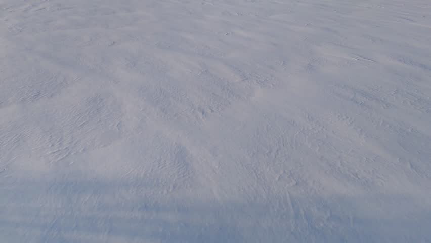 a snowy field with texture from the wind gusts at sunset