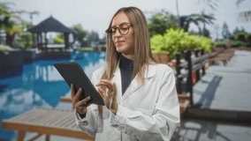 Young woman in white coat holding a tablet and smiling while reaching out with an open hand by a resort pool inside a building; confidence service care. - Powered by Shutterstock - Get 15% off with code: PIKWIZARD15