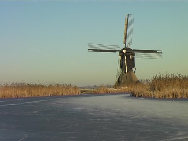 Ice skating along windmill in wintertime in the Netherlands