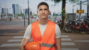 Man engineer holds hardhat and wears high visibility vest at street crosswalk near bicycles and city buildings; determination duty. - Powered by Shutterstock - Get 15% off with code: PIKWIZARD15