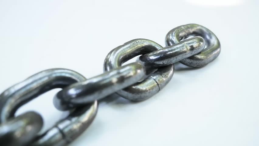 An isolated chain on a plain surface. The metal chain is comprised of connected metal links.