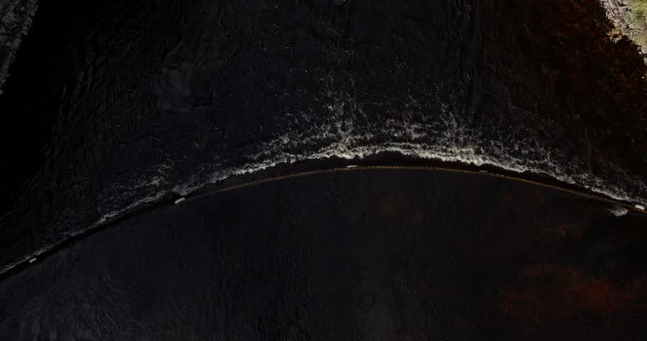 Aerial view of flowing Kalkkinen canal over a curved safety line to prevent people from ending up crashing into Kalkkinen dam, Asikkala, Finland.