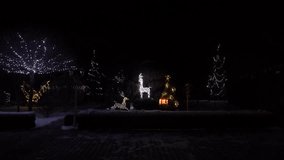 Illuminated Christmas Reindeer Decorations in a Snowy Garden at Night with Glowing Holiday Lights, Festive Trees, and a Bright Gift Box Creating a Magical Winter Atmosphere - Powered by Shutterstock - Get 15% off with code: PIKWIZARD15