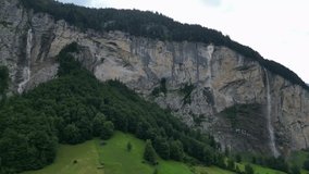 Scenic drone view of multiple alpine waterfalls cascading down the vertical cliffs of Lauterbrunnen valley in the Swiss Alps. - Powered by Shutterstock - Get 15% off with code: PIKWIZARD15