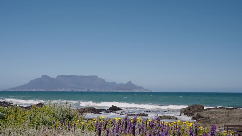 Waves break onto Blouberg shore, with stunning views of Table Mountain, Devil’s Peak, and Signal Hill in Cape Town, Western Cape, South Africa. Perfect coastal nature footage in 4K 30fps.