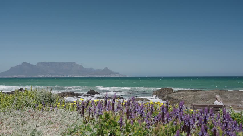 Waves break onto Blouberg shore, with stunning views of Table Mountain, Devil’s Peak, and Signal Hill in Cape Town, Western Cape, South Africa. Perfect coastal nature footage in 4K 30fps.