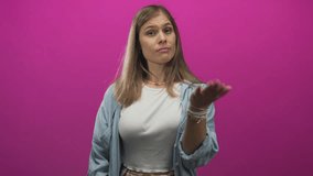 Woman blonde shows open palm and beckons with fingers in studio with magenta backdrop asking for money; pleading need. - Powered by Shutterstock - Get 15% off with code: PIKWIZARD15