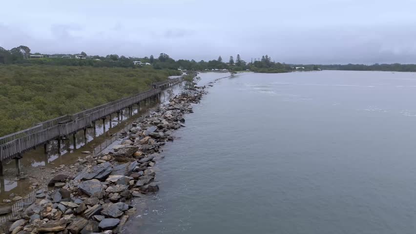 An elevated boardwalk crosses shallow wetlands with trees and rocks scattered through wide calm waters