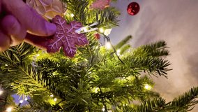 A hand delicately places a charming gingerbread snowflake ornament onto a beautifully decorated Christmas tree, amidst twinkling lights. - Powered by Shutterstock - Get 15% off with code: PIKWIZARD15