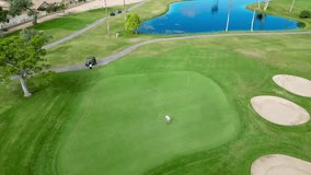 An aerial view of a golf course with players on the green, sand bunkers, and a reflective pond in Mesa, Arizona, USA - Powered by Shutterstock - Get 15% off with code: PIKWIZARD15