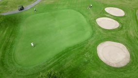 A top-down aerial view of golfers on a Mesa green surrounded by manicured fairways and sand bunkers under bright Arizona daylight, USA - Powered by Shutterstock - Get 15% off with code: PIKWIZARD15