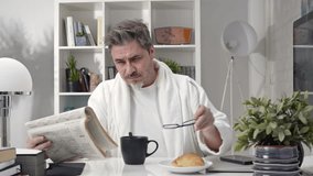 50s man having breakfast drinking morning coffee at home. Businessman checking newspaper for business and stock financial news. - Powered by Shutterstock - Get 15% off with code: PIKWIZARD15