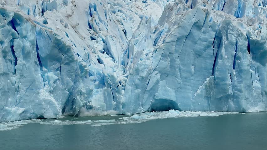A huge ice mass at Argentina Patagonia Lake Argentino Perito Moreno glacier breaks off and crashes into the water, showing powerful natural movement and impact