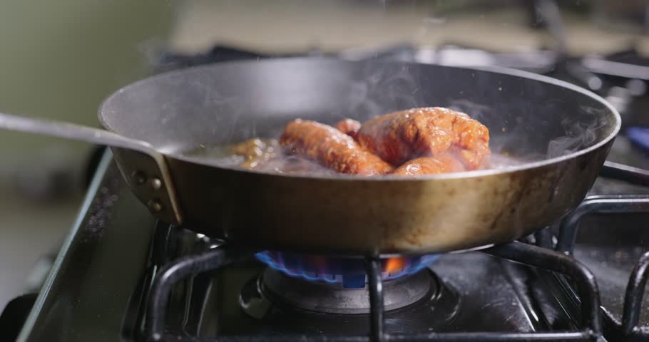 Chorizo Sausages Sizzling and Searing in a Skillet over a Gas Flame