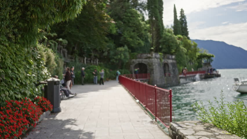 Lakeside promenade with red railing and stone pier, softly blurred shallow focus path; background backplate copyspace calm.