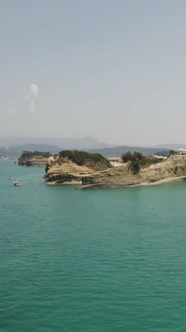 Aerial view of the iconic Canal D’Amour in Sidari, Corfu, on a sunny summer day, showing its turquoise waters and unique sandstone formations.