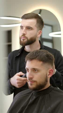 Professional barber giving haircut to client. Clip