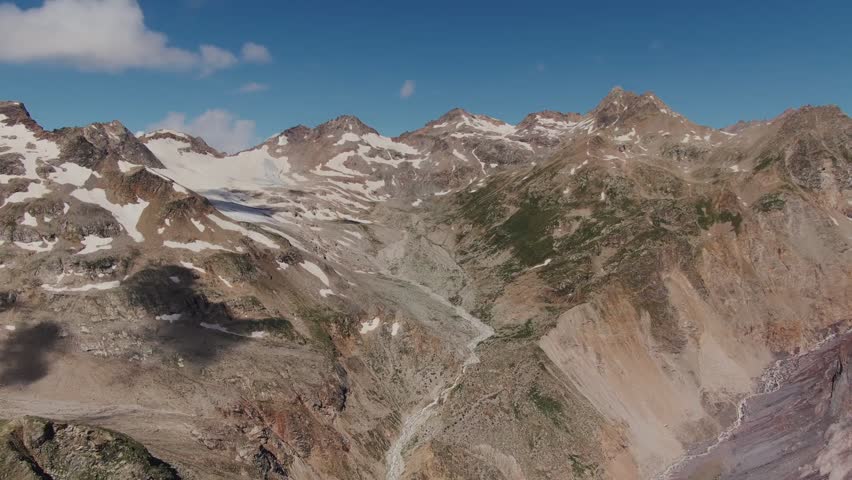 Steep rocky mountains with sharp cliffs and snowy ledges rise through drifting clouds, creating a dramatic, cold, and powerful high-altitude landscape.
