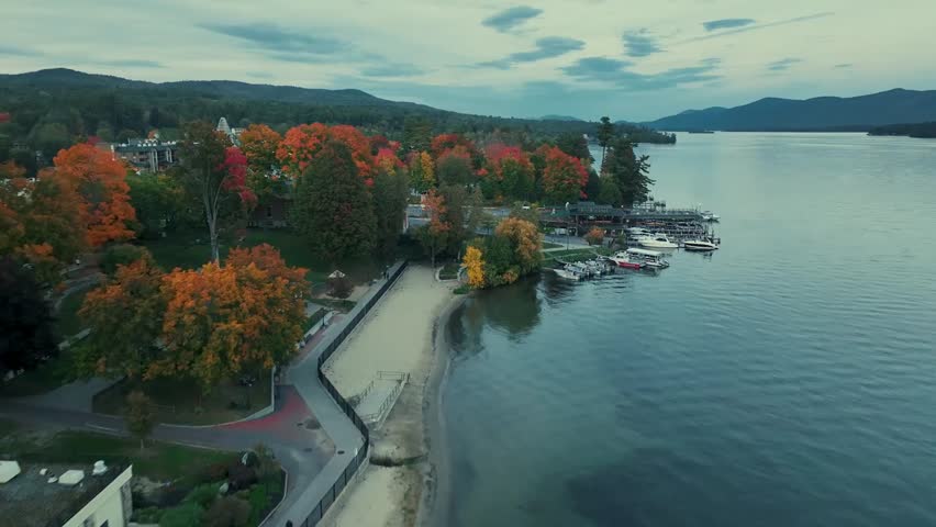Aerial view of a lake surrounded by vibrant autumn foliage, showcasing the colorful trees and serene water reflections.