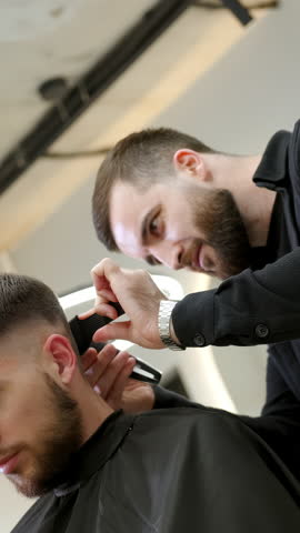 Professional barber giving haircut with electric clipper. Clip